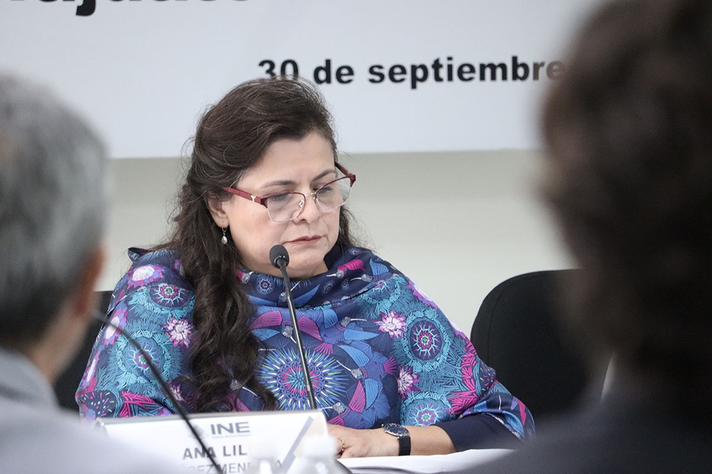 Mujer sentada con lentes frente a un micrófono