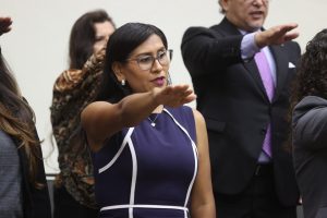 mujer de pie, vestido morado con el brazo derecho extendido al frente
