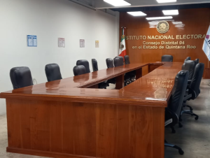 salón con una mesa, una de pared madera y sillones negros