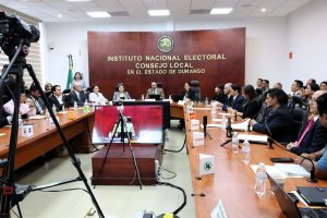 varias personas en un salón con mesa de madera sentadas