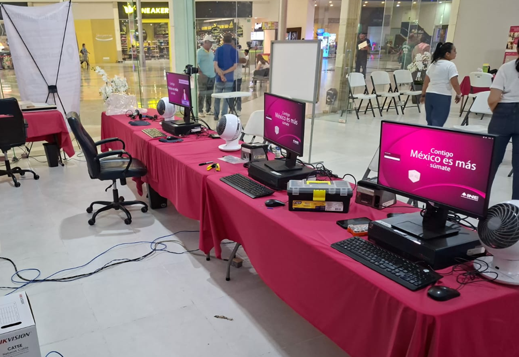 mesas con mantel rosa y computadoras