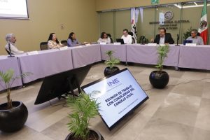 Varias personas sentadas alrededor de una mesa con mantel morado