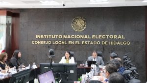 personas sentadas en un salón color gris y letras doradas