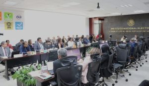 varias personas reunidas en un salón color gris con blanco