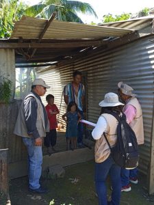 tres personas con chalecos del INE frente a un ciudadano y dos menores de edad